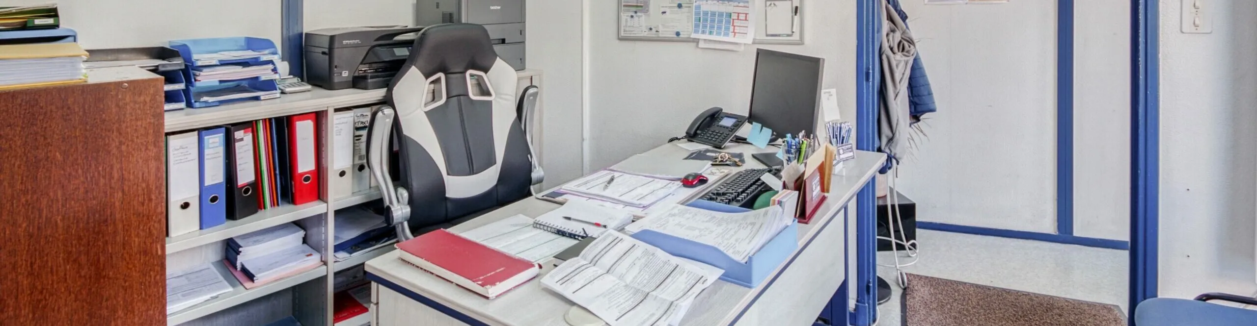Bureau administratif d'agence funéraire avec classeurs, ordinateur et documents de travail